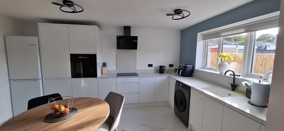 White handleless modern kitchen with island and feature wall
