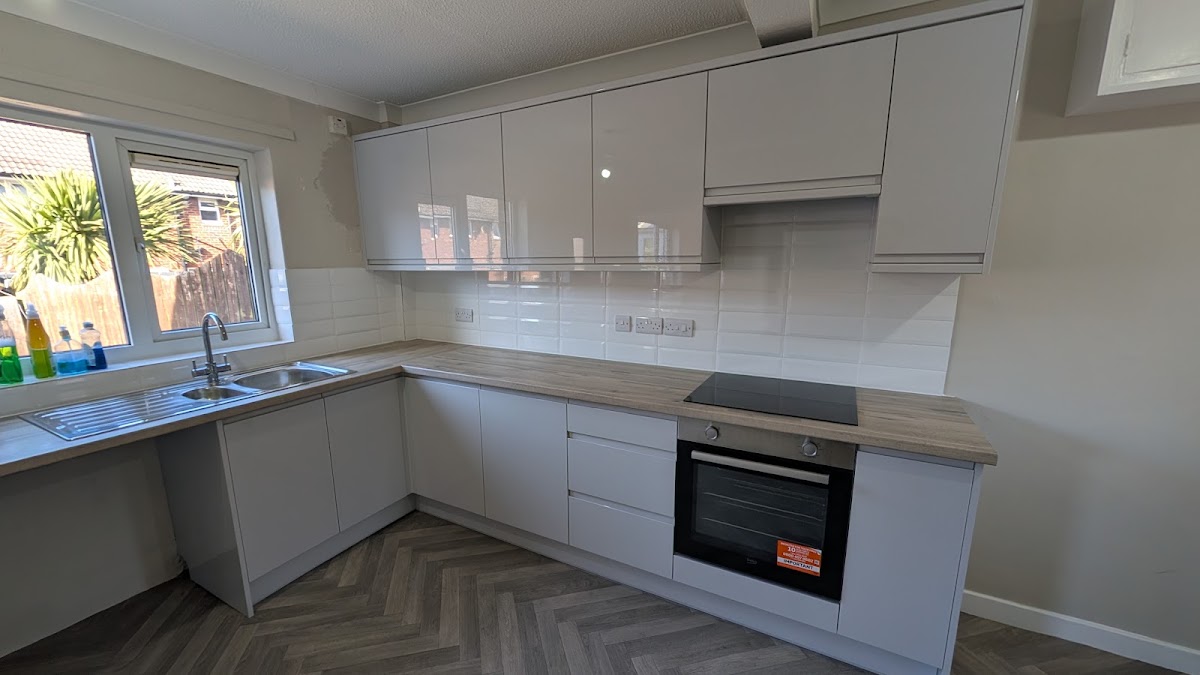 White gloss L-shaped kitchen with herringbone flooring